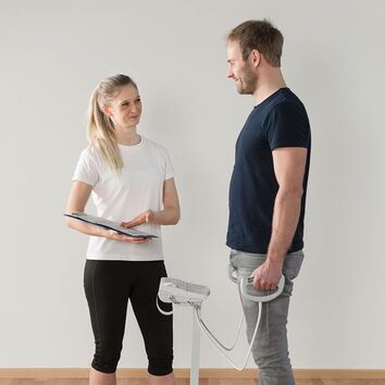 Bioimpedanzanalyse Mann steht auf einer Biawaage und wird von einer blonden Frau getestet