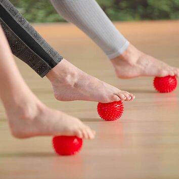 Fussfaszienmassage mit Faszienkugel Fussmassager mit Hilfe eines roten Igelballs