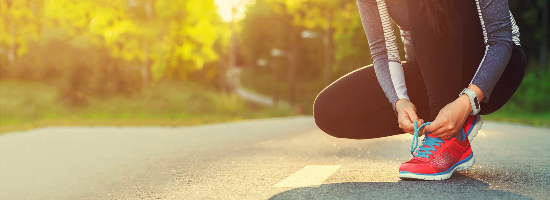 Laufkurs SPORTIVATION Frau bindet sich Laufschuh zu