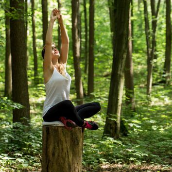 Länger fit in Beruf und Alltag - Workshop Frau sitz im Yogasitz auf einem Baumstumpf