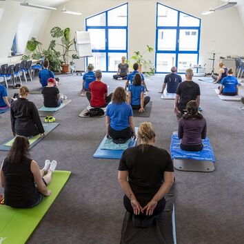 Rückengesundheit_ Workshop Gruppe Mitarbeiter im Sitz auf der Matte während eines Rückenworkshops