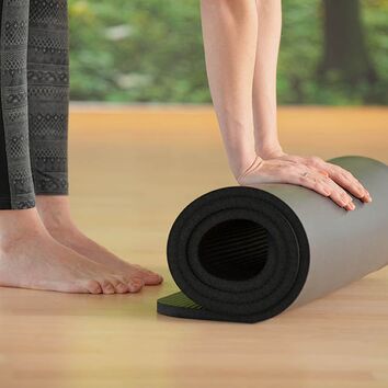 Yogamatte Teilnehmerin rollt schwarze Yogamatte  zusammen
